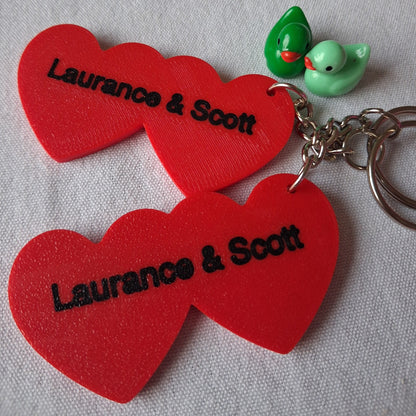 Red heart-shaped keychains with 'Laurence & Scott' branding on a gray background