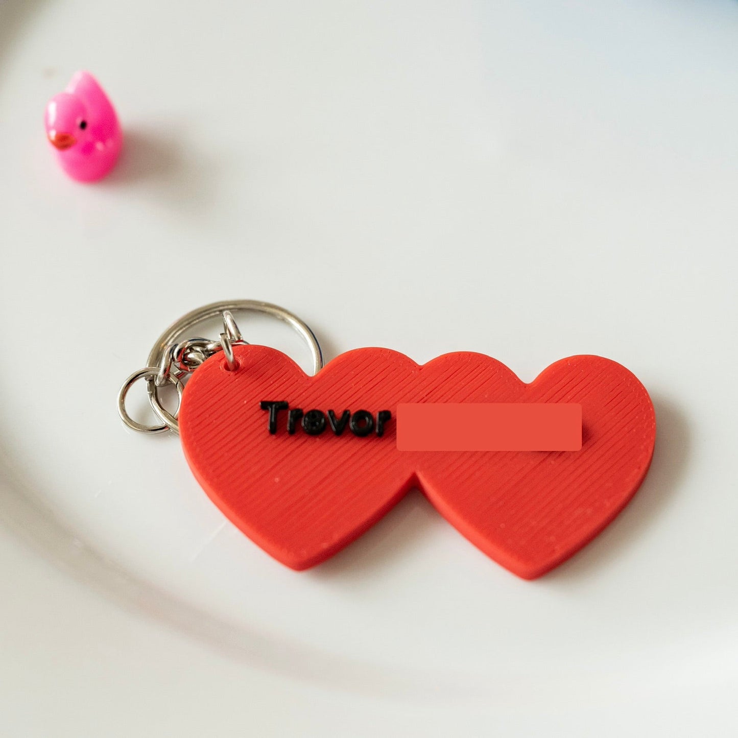 Red heart-shaped keychain with 'Trevor' on a white background